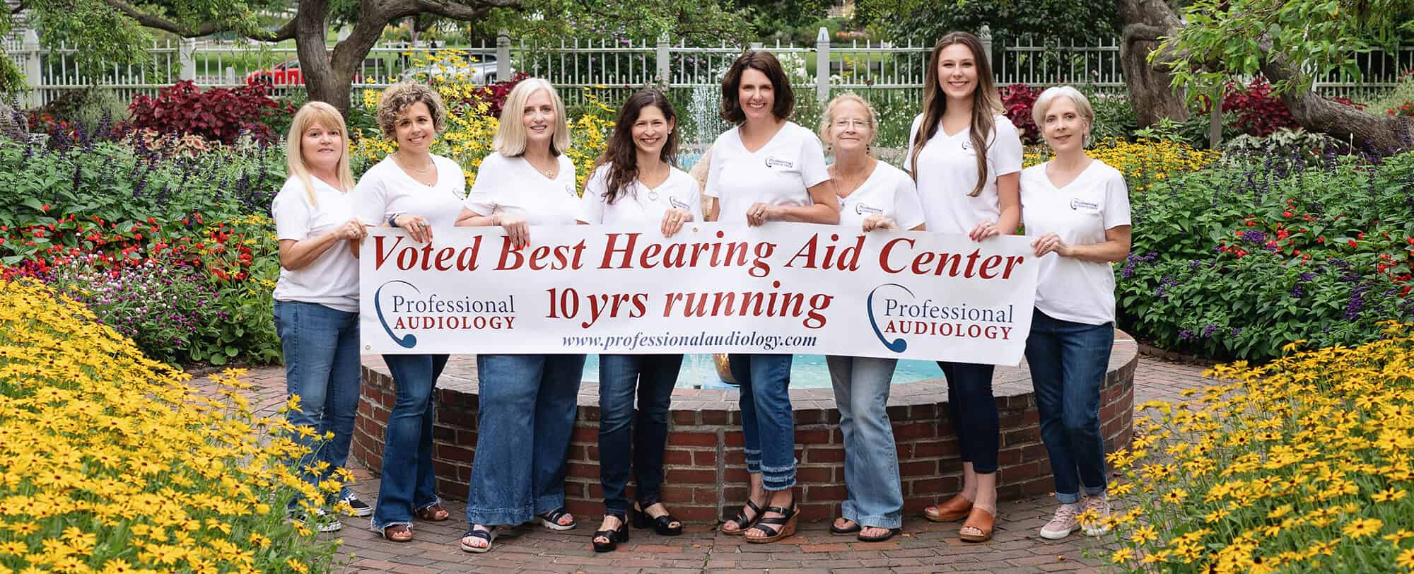 Professional Audiology staff holding large banner