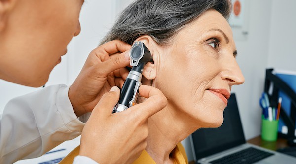 woman looking into patients ear with an otoscope